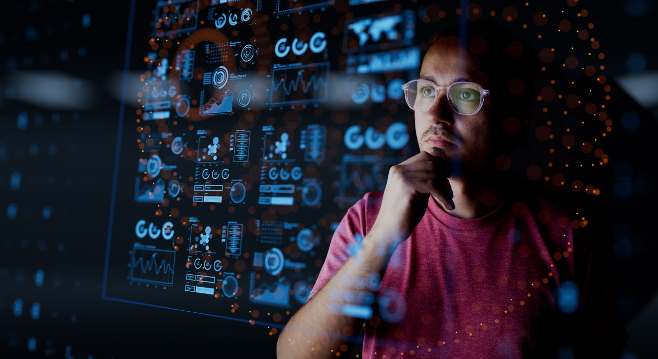 Uma pessoa de óculos e camisa cor-de-rosa analisa atentamente os dados digitais num ecrã transparente