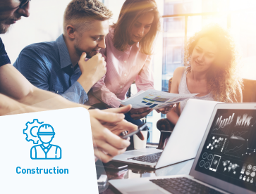 A equipa trabalha em conjunto em torno de uma mesa, analisando os planos de construção com computadores portáteis a exibir os projetos.